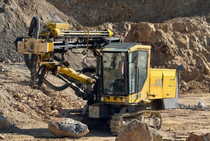 Gelbes Bohrgerät auf Raupenfahrwerk beim Bohren von Sprenglöchern im Gesteinsabbau.