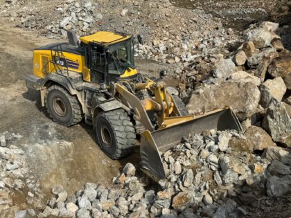 Komatsu WA475 Radlader beim Aufnehmen von grobem Felsmaterial, Nahaufnahme Frontschaufel.